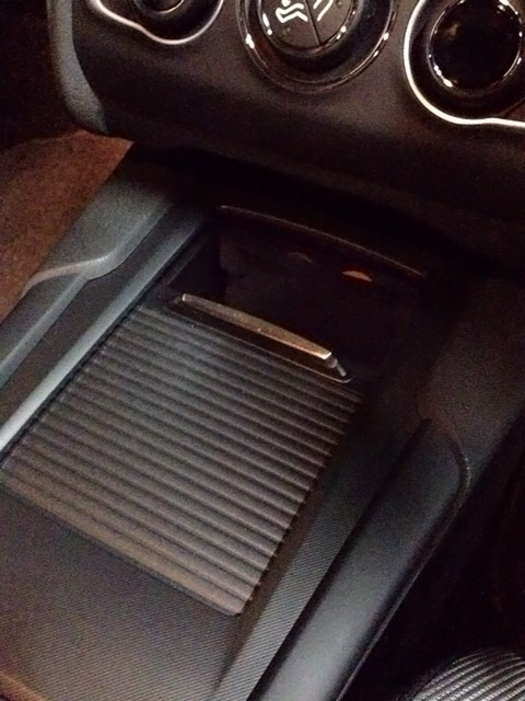 ちょっと暗くて分かりにくいが、スライド式の蓋を開けるとオレンジに見えるのがシガーライターソケット。この写真では見えないが、そこにはさらに引き出し式の小物入れがある。 ちょっと暗くて分かりにくいが、スライド式の蓋を開けるとオレンジに見えるのがシガーライターソケット。この写真では見えないが、そこにはさらに引き出し式の小物入れがある。